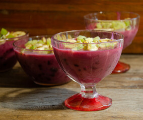 Homemade fruit dessert in a glass cup, on a wooden table.