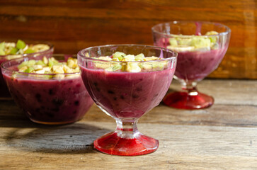 Homemade fruit dessert in a glass cup, on a wooden table.