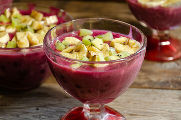 Homemade fruit dessert in a glass cup, on a wooden table.