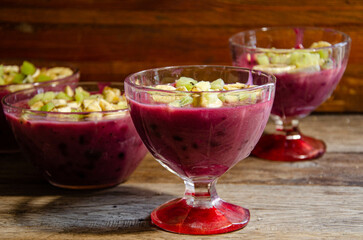 Homemade fruit dessert in a glass cup, on a wooden table.