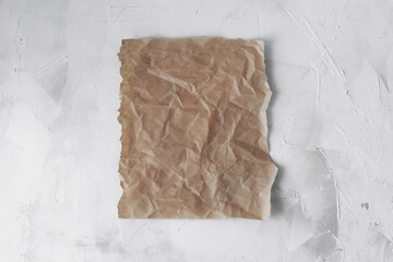 Empty space for the text . A piece of brown crumpled parchment paper on a light background.