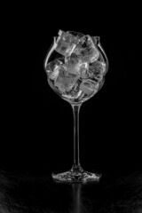 Wine glass full of ice on a black background. Back light.