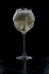 Wine glass full of ice and sparkling wine on a black background. Back light.