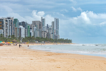 Beautiful day at the beach of Boa Viagem in Recife, Pernambuco state, Brazil. People on the beach, the sand strip, the sea and the city buildings on background.