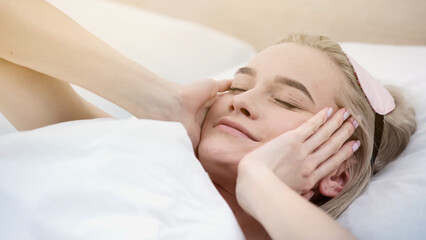 cheerful blonde woman with sleeping mask waking up in bed