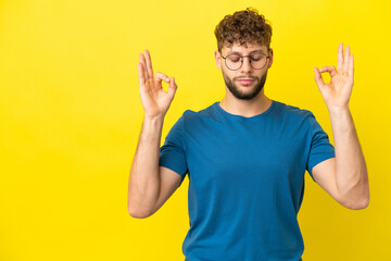 Young handsome caucasian man isolated on yellow background in zen pose