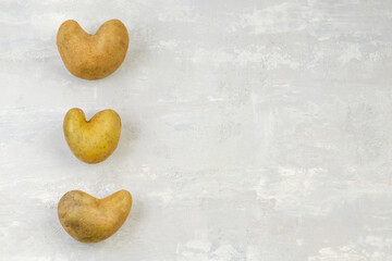 Obraz premium Some ugly heart-shaped potatoes on a gray background. Funny concept of vegetables or food waste. Top view. Copy space.