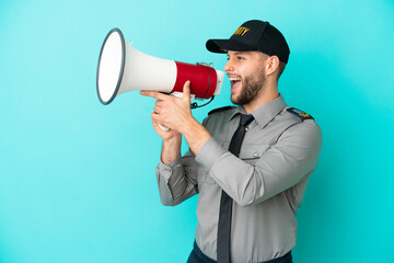 Young security man isolated on blue background shouting through a megaphone