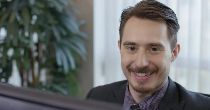 Corporate Happy Brunette Man Working on a Desktop Computer then Smiling at Viewer - 35mm Closeup Tripod Shot 4K