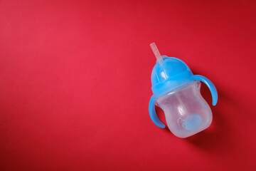 Baby bottle for drinking with water, on a red background