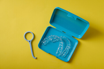 Container with plastic mouthguards on a yellow background, top view