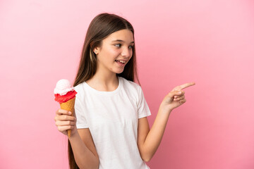 Little girl with a cornet ice cream over isolated pink background pointing finger to the side and...