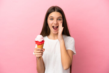 Little girl with a cornet ice cream over isolated pink background with surprise and shocked facial...