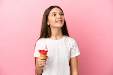 Little girl with a cornet ice cream over isolated pink background laughing