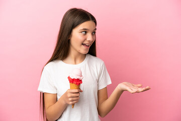 Little girl with a cornet ice cream over isolated pink background with surprise expression while looking side