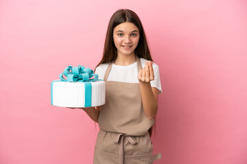 Little girl with a big cake over isolated pink background making money gesture