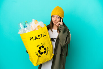 Little girl holding a bag full of plastic bottles to recycle over isolated blue background thinking...