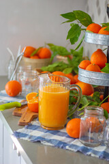 Freshly squeezed mandarin orange juice with glass pitcher, glass jars and aluminum reusable straws.