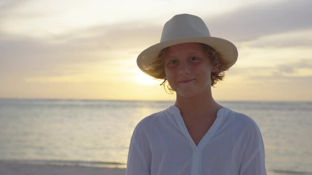 Portrait happy little child boy in yellow hat. Cinematic portrait of happy boy looking at the camera, sunset rays in the background
