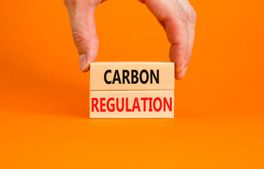 Carbon regulation symbol. Concept words Carbon regulation on wooden blocks on a beautiful orange table orange background. Businessman hand. Business and carbon regulation concept, copy space.