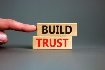 Build trust symbol. Concept words Build trust on wooden blocks on a beautiful grey table grey background. Businessman hand. Business and build trust concept, copy space.