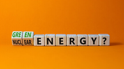 Nuclear or green energy symbol. Turned wooden cubes and changed concept words nuclear energy to green energy. Beautiful orange background copy space. Business nuclear green energy concept.