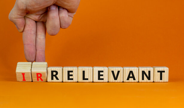 Relevant or irrelevant symbol. Businessman turns wooden cubes changes the word irrelevant to relevant. Beautiful orange table orange background. Business, relevant or irrelevant concept. Copy space.