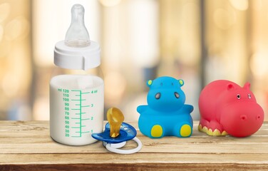 Bottles of milk for baby with toys on table in kitchen background