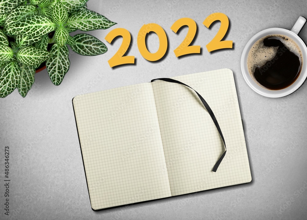 Wall mural New year goals 2022 on desk. A table with coffee cup, notebook and plant. Resolutions, plan, goals, business concept.