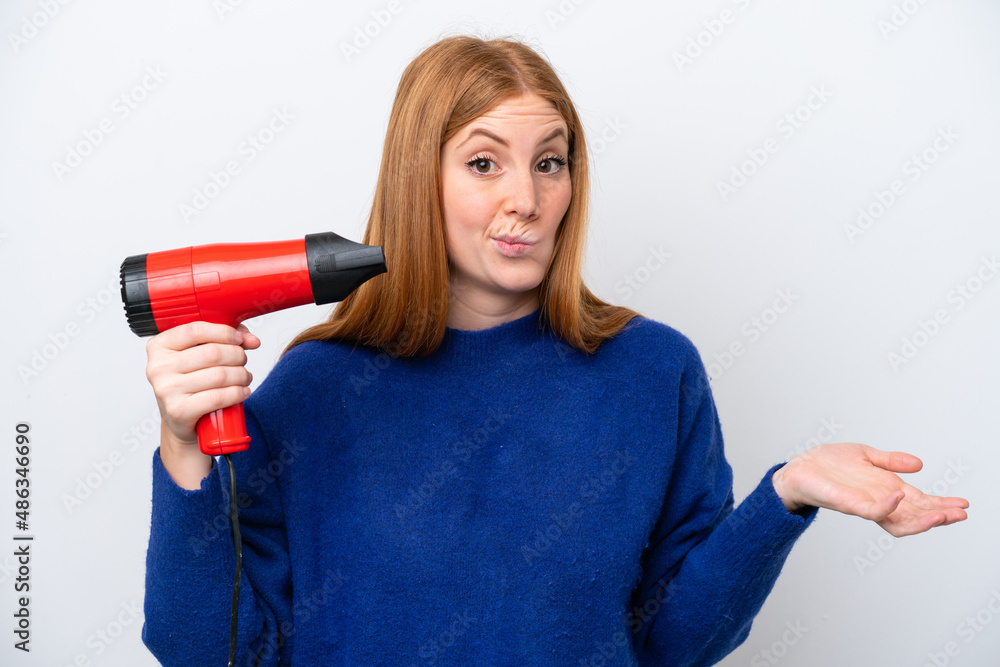 Wall mural Young redhead woman holding a hairdryer isolated on white background making doubts gesture while lifting the shoulders