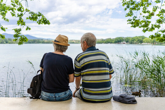 Senior couple resting on a bench by lake of Banyoles, Catalonia, Spain