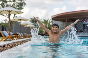 Asian Young Boy Having a good time in swimming pool, He Jumping and Playing a Water in Summer. - 486348434
