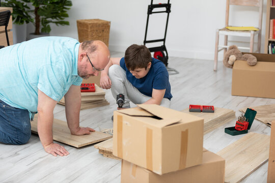 A father and son review how to assemble a new bookcase. - Powered by Adobe