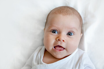 Portrait of a cute newborn happy baby on a white background, top view. The kid with the big eyes