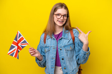 Teenager Russian girl holding an United Kingdom flag isolated on yellow background giving a thumbs up gesture