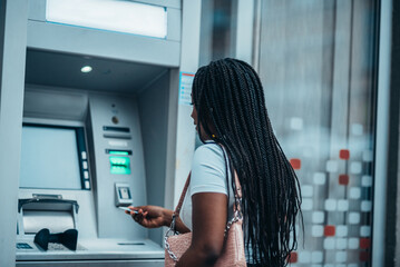 Young african american woman using credit card and an atm machine