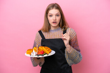 Teenager Russian girl holding a waffles isolated on pink background intending to realizes the solution while lifting a finger up