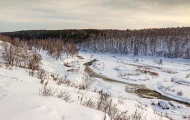 Winter landscape with trees and sky from the high rocky river bank