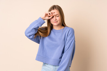 Teenager Ukrainian girl isolated on beige background with tired and sick expression