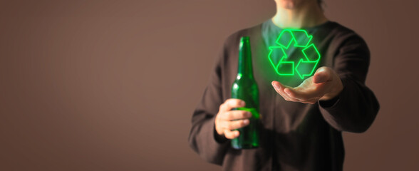 Woman hold green light recycle symbol and empty glass of beer bottle in other hand. Young woman in showing the recycle sign isolated on a background. Sustainability concept. Banner with copy space.