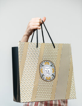PARIS, FRANCE - DEC 2, 2018: French woman holding paper bag from Diptyque a Paris-based luxury goods company that produces a high-end line of scented candles, perfumes, face and body care