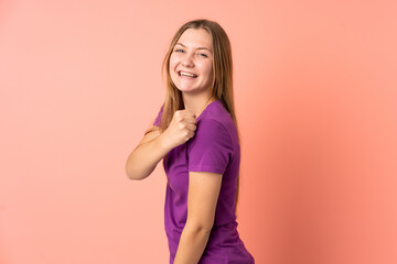 Teenager Ukrainian girl isolated on pink background celebrating a victory