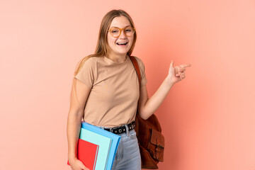 Teenager Ukrainian student girl isolated on pink background surprised and pointing finger to the side