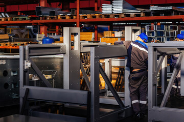 Factory workers assembling metal equipment in workshop