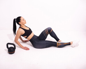 Strong fitness woman sitting on the floor isolated on white