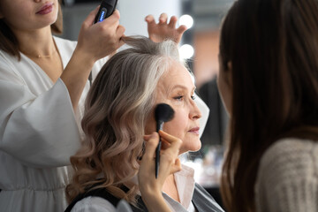 Elderly woman getting make-up and styling in a beauty salon