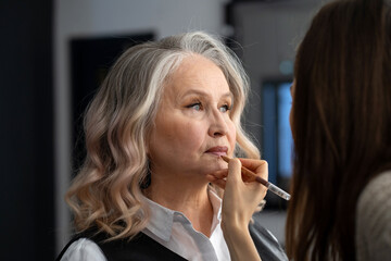 Beautiful elderly woman getting make-up in a beauty salon