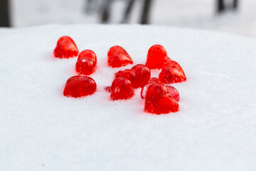 Closeup set of small bright red glass hearts on powdery snow of snowdrift at cold winter day in park forest, symbol of romantic love, St. Valentine's Day holiday concept, low angle shoot