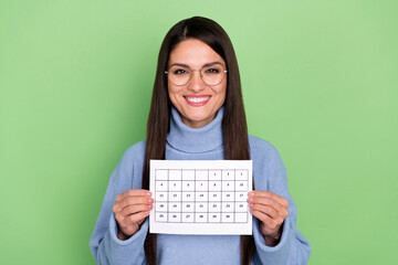 Photo of clever young brunette lady hold calendar wear blue pullover isolated on green color background