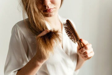 a girl with problematic hair sits on the bed and combs them. girl with a comb sits on a bed in pajamas